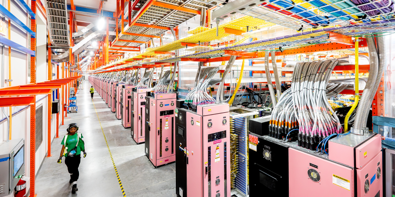 A data center technician walking within a data center hall near UltraServers.